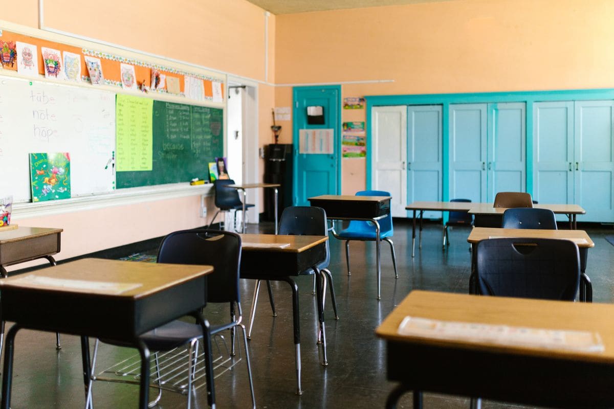 An empty, colourful primary school classroom with rows of desks and chairs